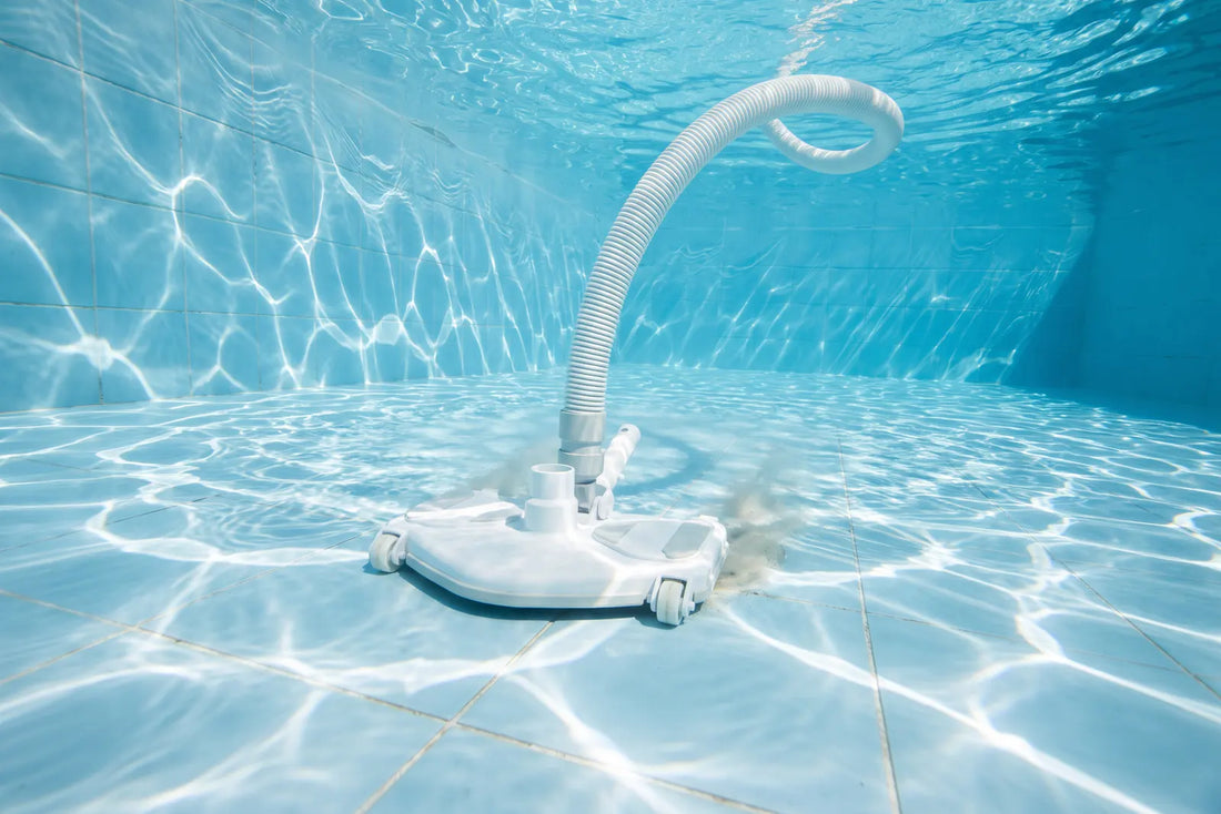 Limpiafondos triangular aspirando el fondo de una piscina de agua clara