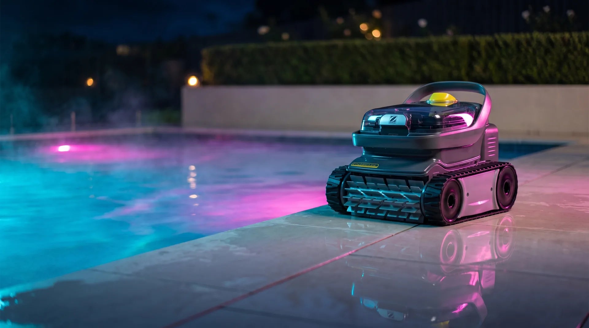 Robot limpia piscinas Zodiac junto a una piscina iluminada de noche