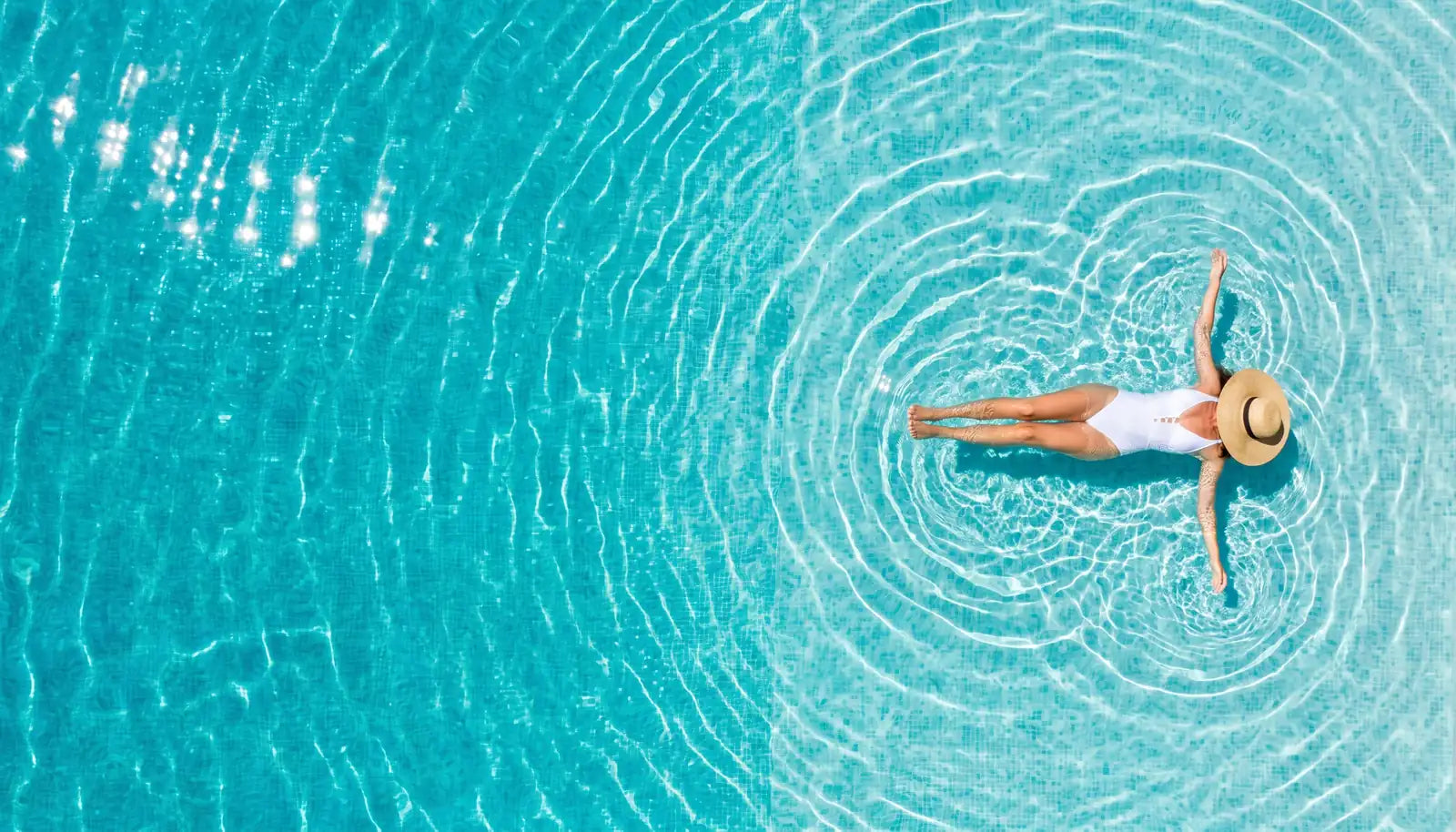 Mujer flotando en el agua cristalina de una piscina vista desde arriba